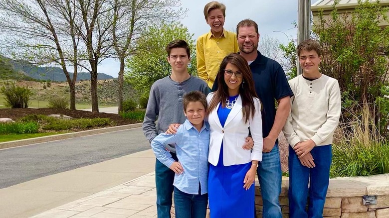 The Boebert family smiling and posing together outside on a sunny day.