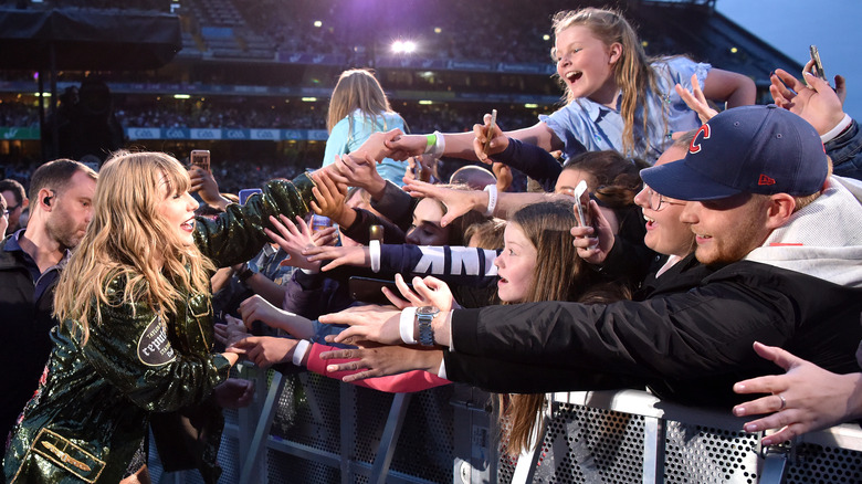 Taylor Swift touching the hands of fans during the Reputation tour