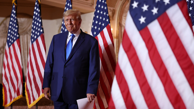 Donald Trump standing next to American flags