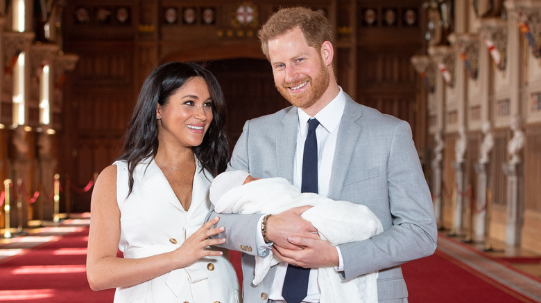 Meghan Markle and Prince Harry smiling alongside baby Archie