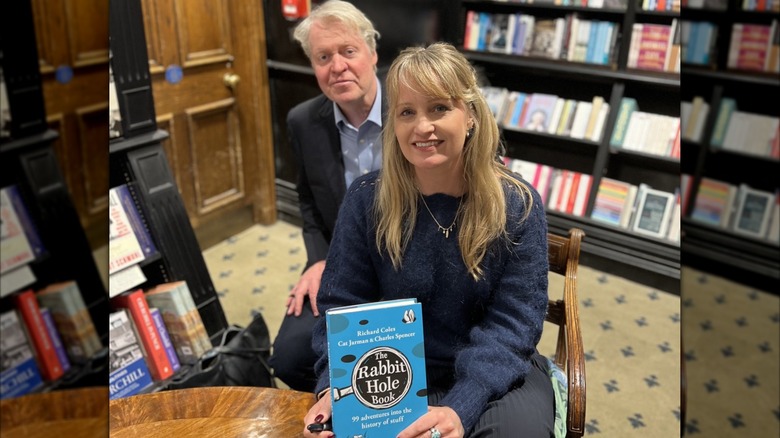 Cat Jarman sitting in a bookstore, book in hand, with Charles Spencer peering around her shoulder.