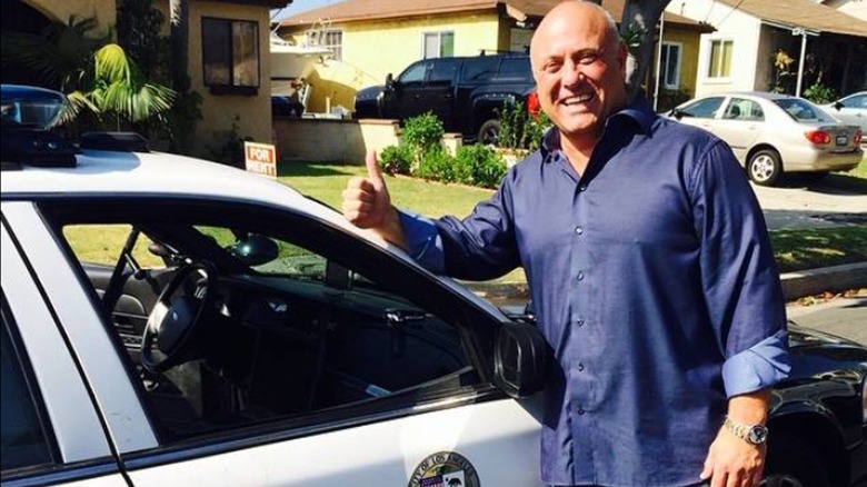 Charles 'Todd' Hill smiles next to a police car