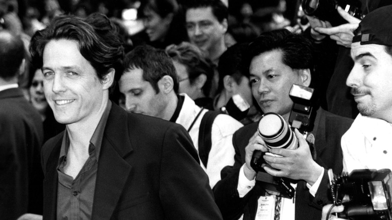 young Hugh Grant flanked by the paparazzi