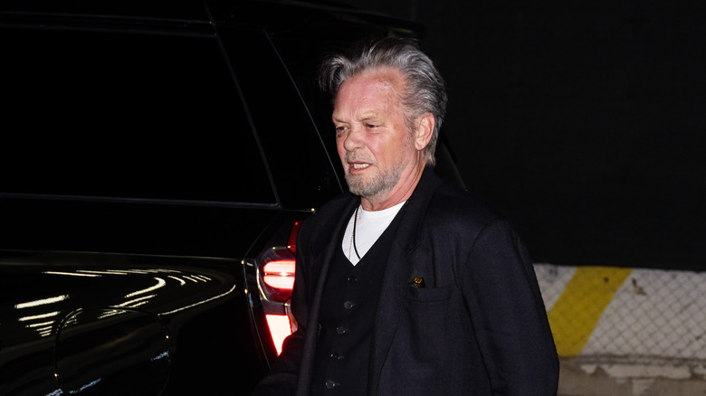 John Mellencamp walking beside a pickup truck