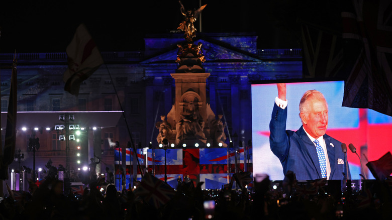 King Charles on big screen in front of Buckingham Palace