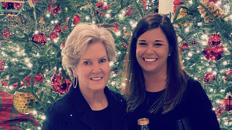 Susie Wiles and Caroline Wiles stand in front of Christmas trees