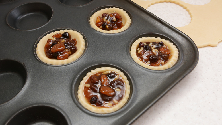 mini pies going into a muffin baking sheet 