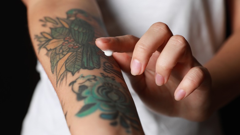 Woman applying cream to new tattoo