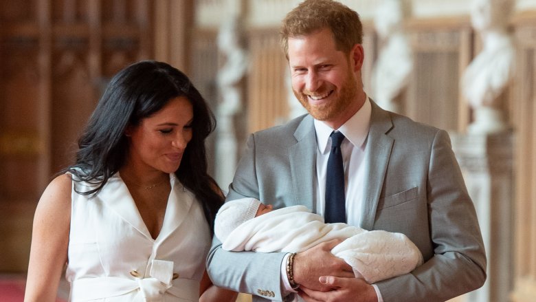 Harry holding baby as Meghan smiles at son