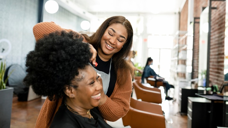 Black woman getting her hair styled by a Black stylist