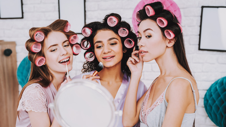 Three women applying makeup