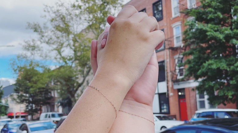 Two people with permanent bracelets holding hands