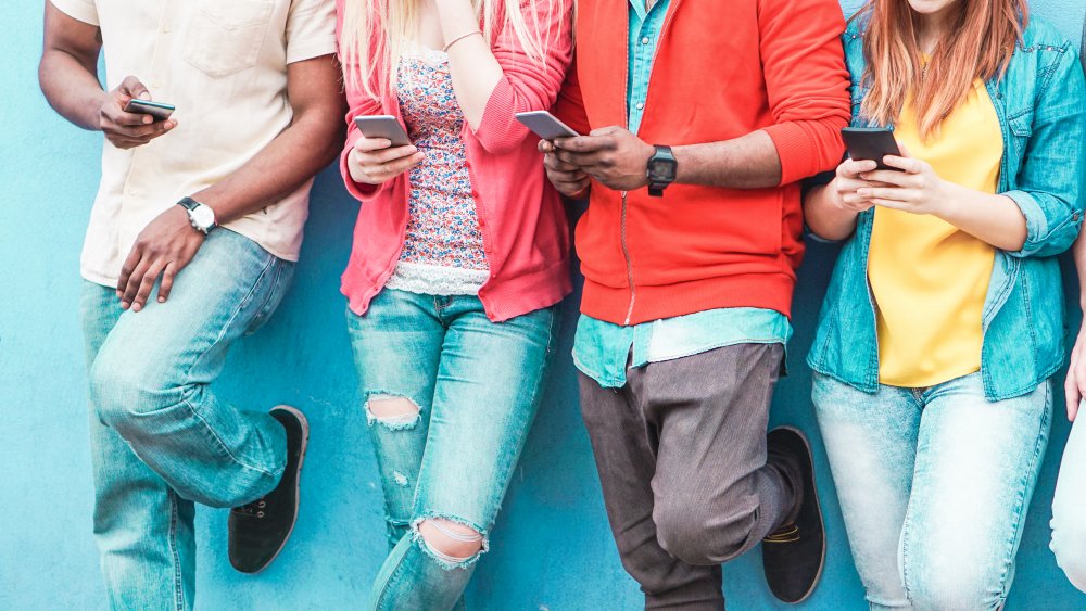 Four people on their phones, focused on the midsection