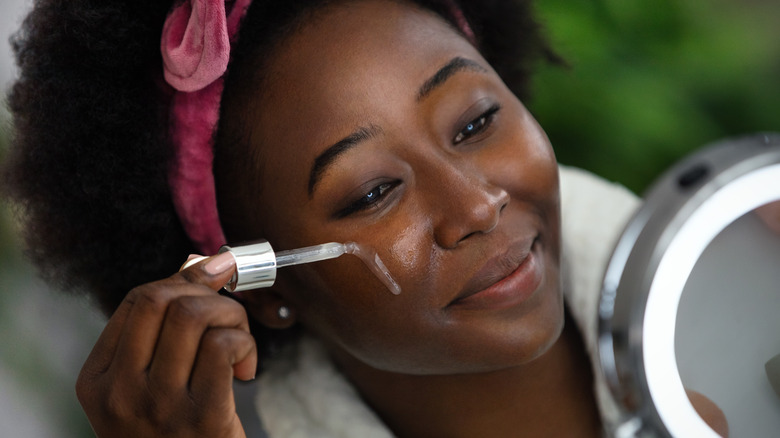 woman applying serum on face