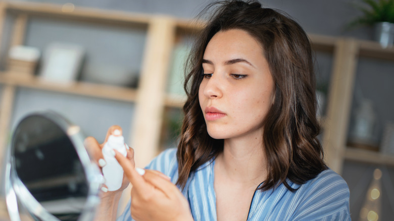 woman applying lotion with mirror