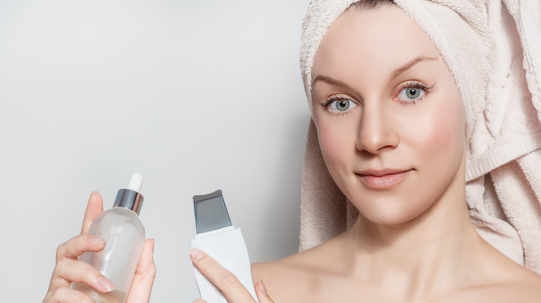 A woman holding the skin spatula and a spray