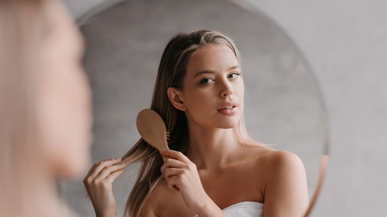 Woman brushing hair in mirror