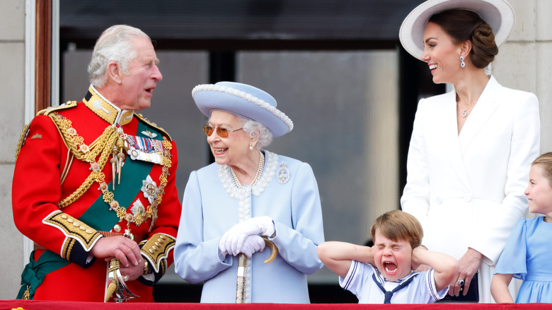 Prince Charles, Queen Elizabeth, and Kate Middleton ignore Prince Louis as he makes faces.