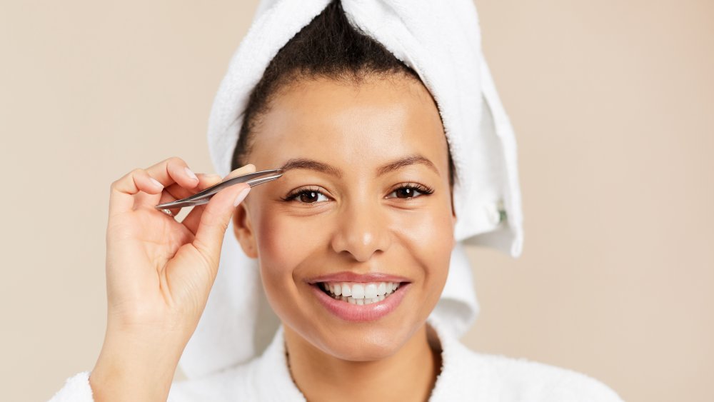 Woman in 30s plucking eyebrows