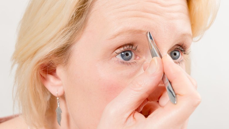 woman tweezing eyebrows