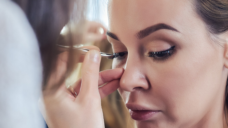 woman gluing on false lashes