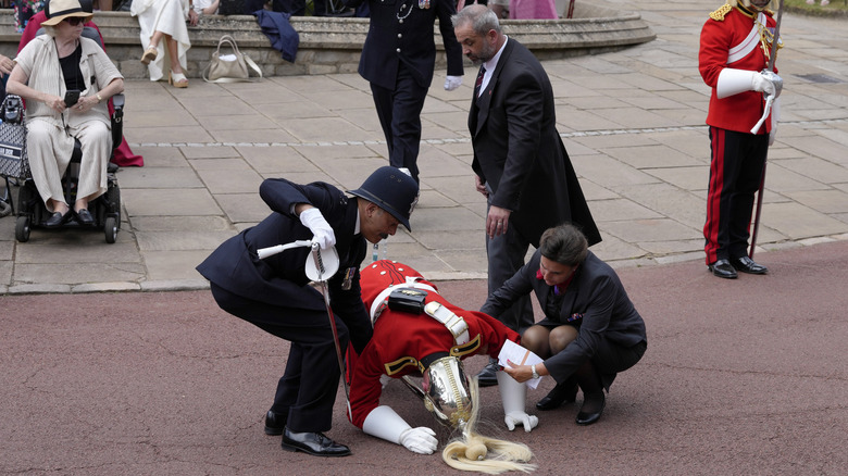 British royal guard being helped after falling outside