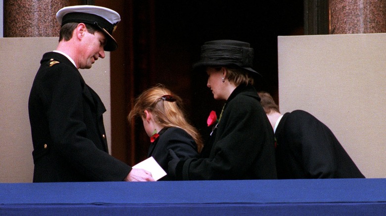 A young Princess Beatrice is helped to her feet by Timothy Laurence and the Countess of Wessex after fainting on a balcony during a service