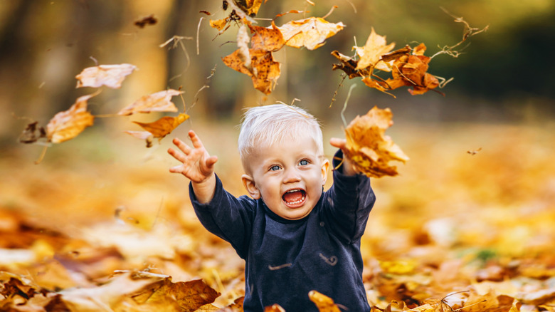 blonde baby throwing leaves