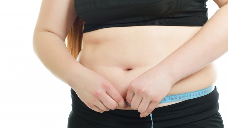 A woman measuring her body's abdomen, close-up