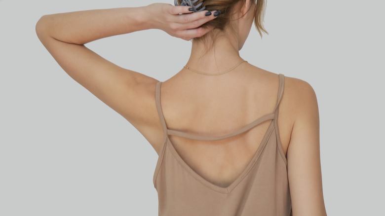 Woman wearing camisole faces away from camera