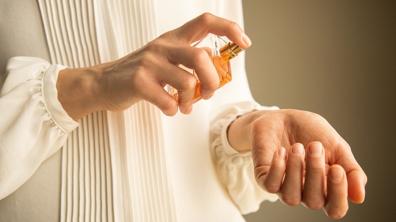 Woman applying perfume to wrist