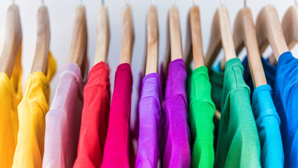 Fast fashion inexpensive shirts of different colors on hangers, fashion trends that aren't worth the money