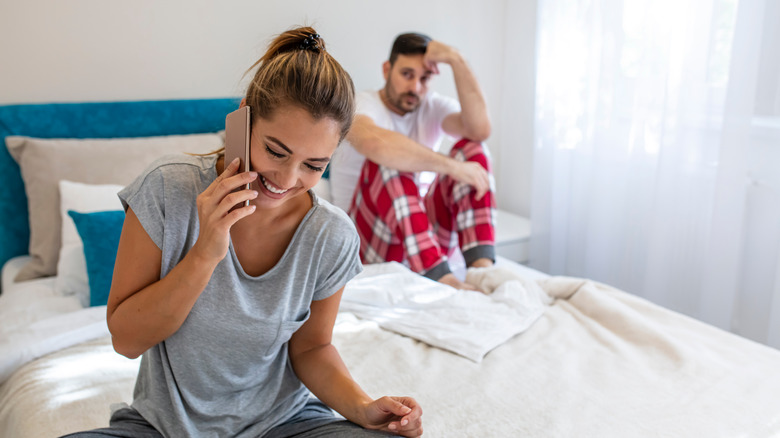 smiling woman on phone with unhappy man