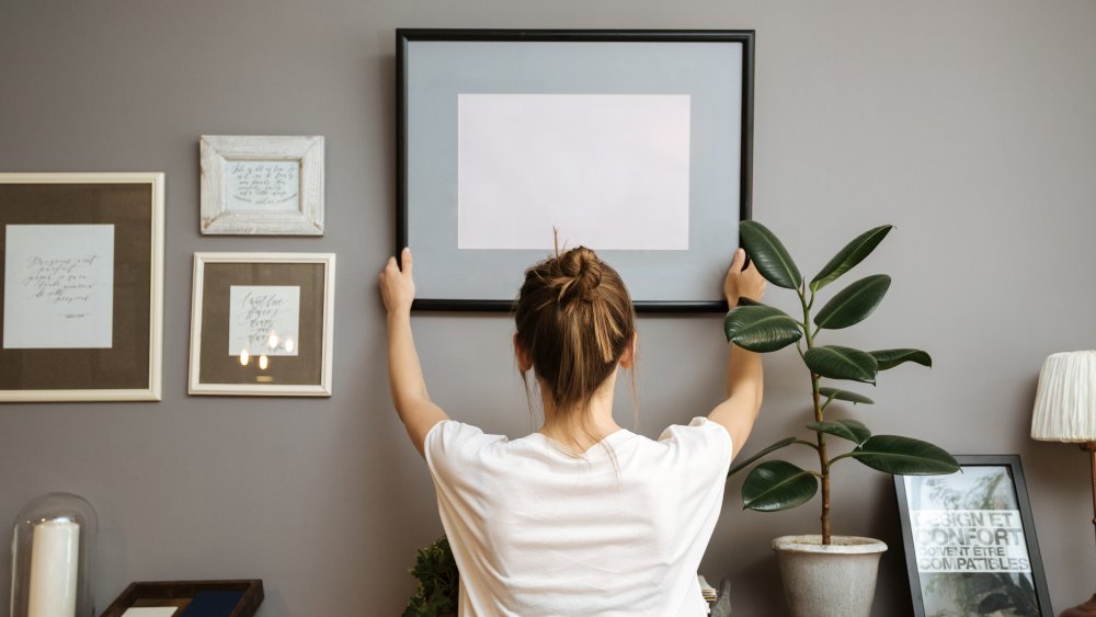 Woman hanging picture in home