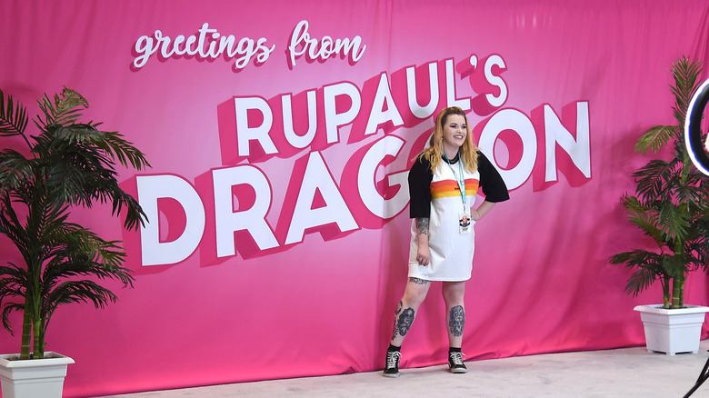 Fan posing in front of RuPaul's DragCon sign