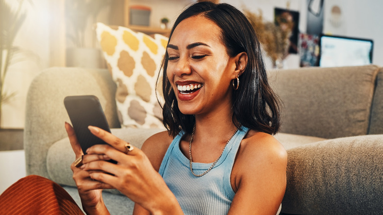 A woman smiling at her phone