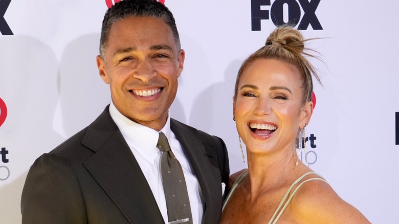 TJ Holmes and Amy Robach smiling on a step and repeat