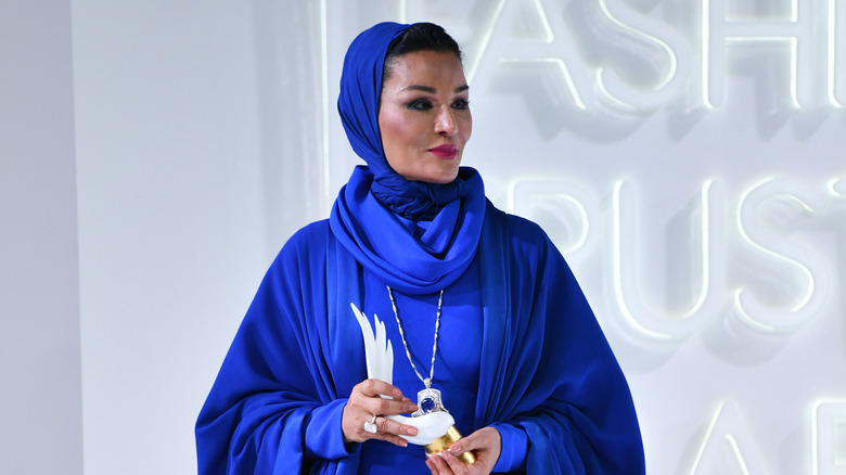 Sheikha Mozah wearing blue, looking on