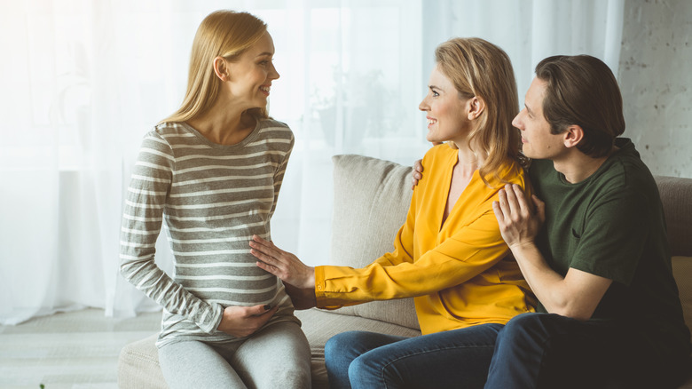 Couple expressing happiness while talking to surrogate expectant mother