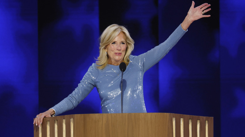 Jill Biden behind podium with arm raised in blue sparkly dress