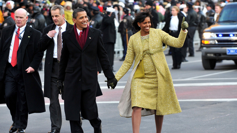 Barack Obama walking hand and hand with michelle obama in yellow sparkly outfit