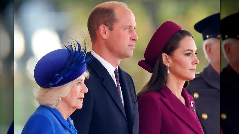 Queen Camilla, Prince William, and Catherine, Princess of Wales all looking serious