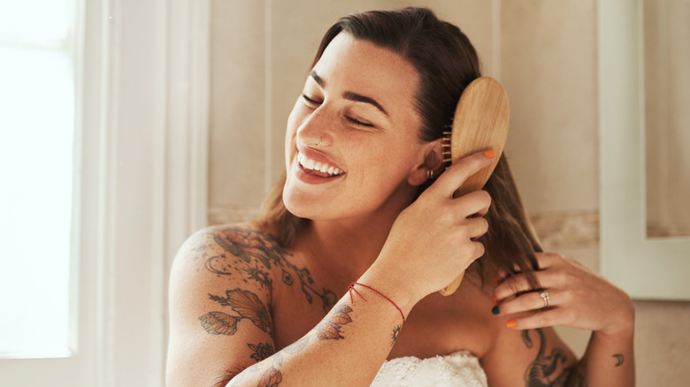 woman smiling and brushing hair with flat brush