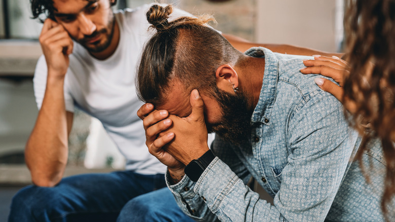 people comforting sad man