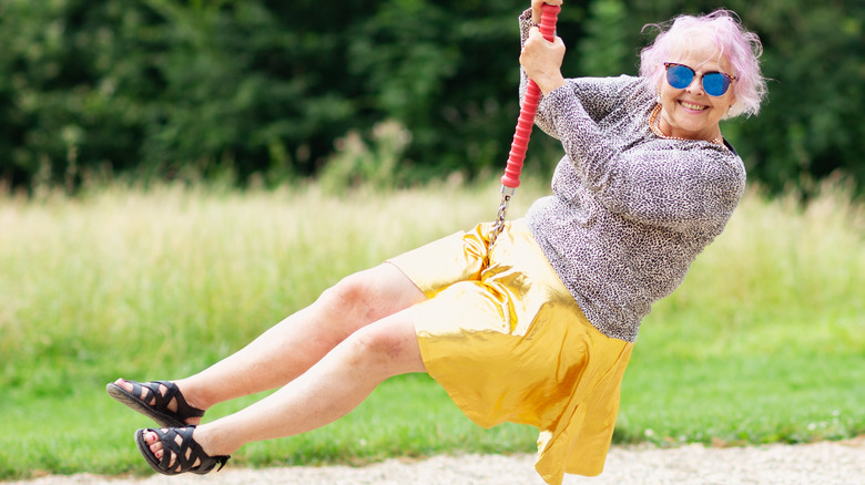 quirky elderly lady on a swing smiling