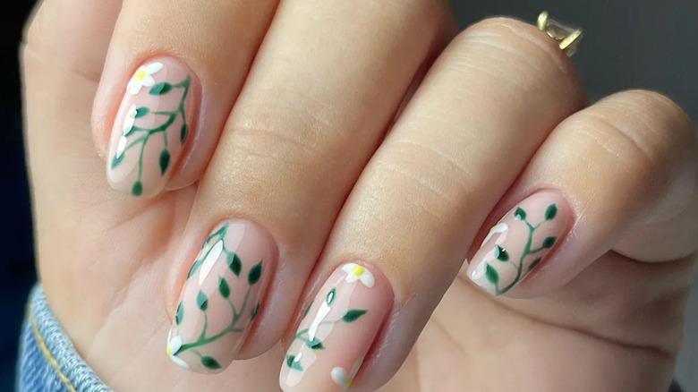 Nude nails with green vine nail art and white daisy blooms.