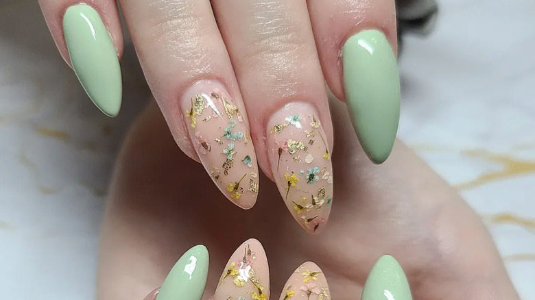 Mint green acrylic nails with dried flower accent nails.