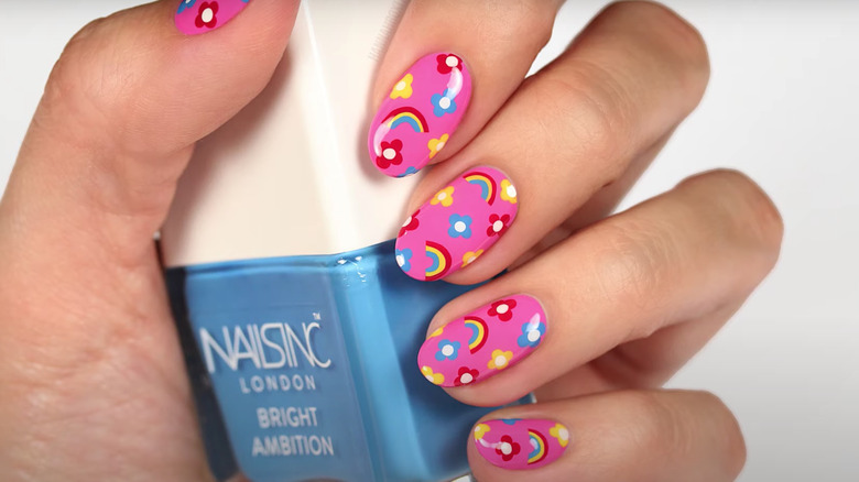 Oval hot pink nails decorated with rainbows and colorful flowers