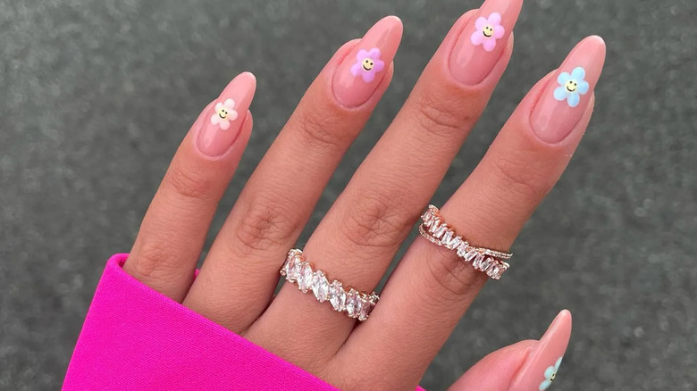 A manicure featuring five-petal flowers with smiley face centers.