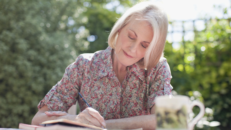 older woman writing in journal